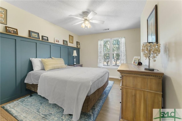 bedroom featuring hardwood / wood-style flooring, ceiling fan, and a textured ceiling