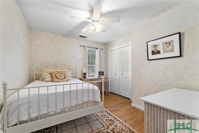 bedroom featuring hardwood / wood-style floors, a textured ceiling, a closet, and ceiling fan