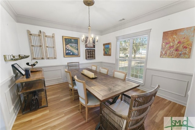 dining space featuring crown molding, a chandelier, and light hardwood / wood-style flooring