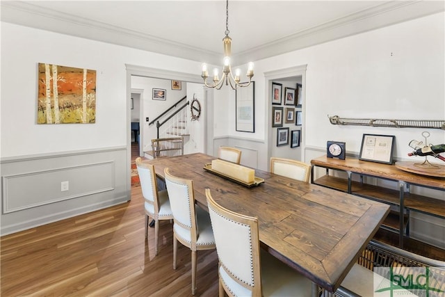 dining area featuring an inviting chandelier, ornamental molding, and wood-type flooring