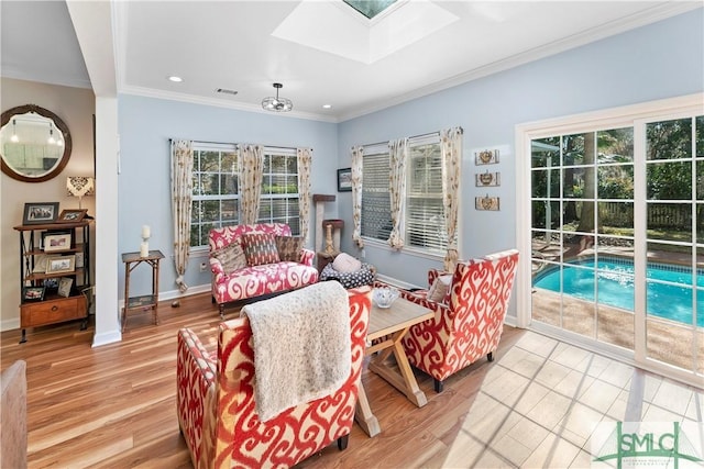 living room featuring ornamental molding, a skylight, and light hardwood / wood-style floors