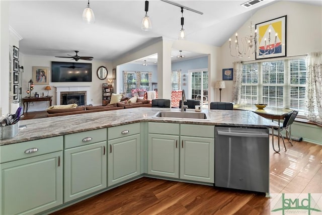 kitchen featuring sink, vaulted ceiling, hanging light fixtures, stainless steel dishwasher, and a fireplace