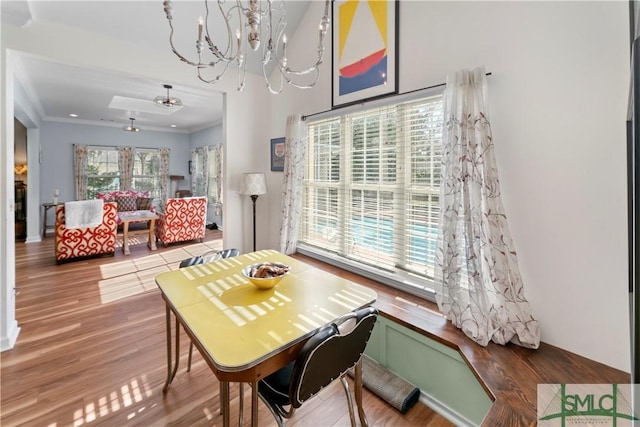 dining room with hardwood / wood-style flooring, crown molding, and a notable chandelier