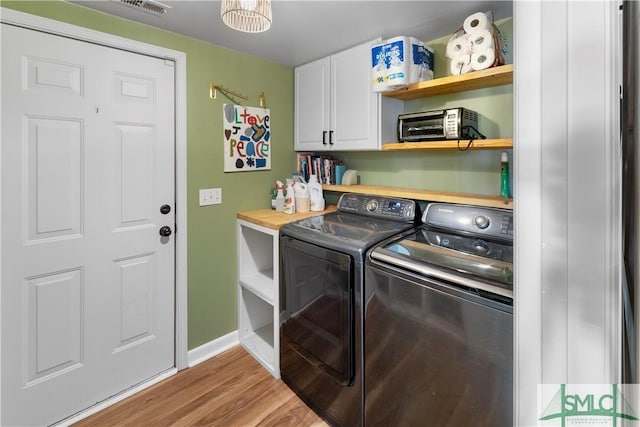 laundry area featuring cabinets, washing machine and dryer, and light wood-type flooring