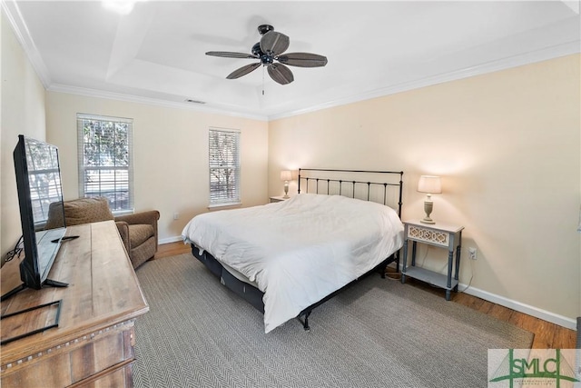 bedroom featuring hardwood / wood-style floors, a tray ceiling, ornamental molding, and ceiling fan