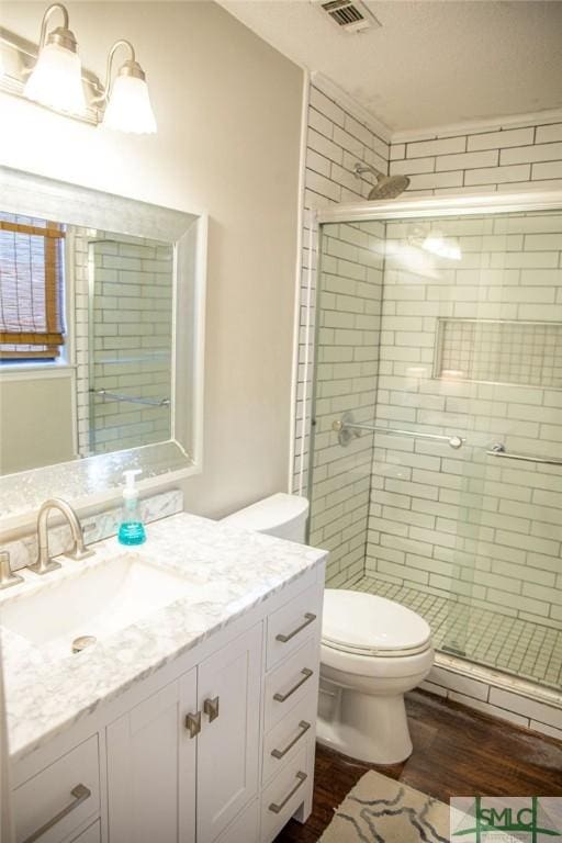 bathroom with vanity, toilet, hardwood / wood-style floors, and walk in shower