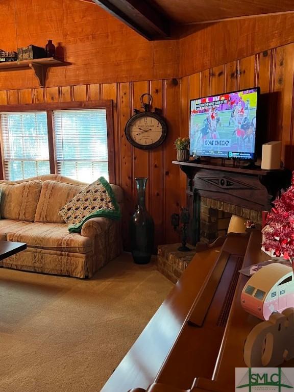 carpeted living room with a fireplace, wooden walls, and lofted ceiling with beams