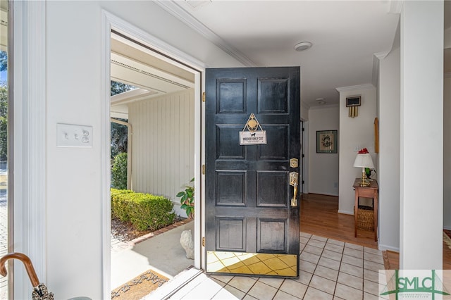 entrance foyer with crown molding and light tile patterned floors