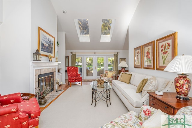 living room featuring a skylight, a tile fireplace, high vaulted ceiling, and french doors