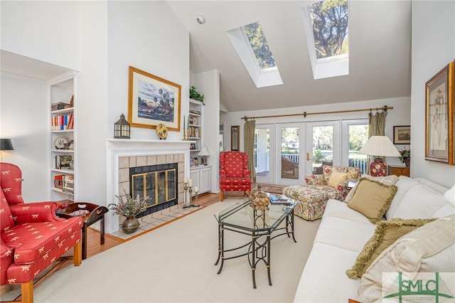 living room featuring hardwood / wood-style flooring, a fireplace, built in features, and french doors