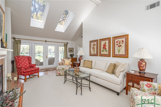 living room featuring a skylight, high vaulted ceiling, and french doors