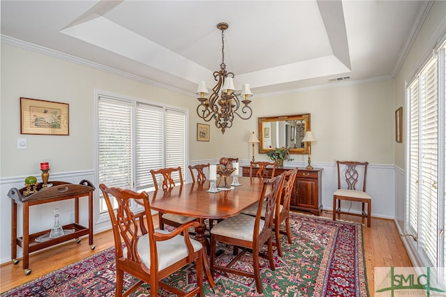 dining space with a tray ceiling, light hardwood / wood-style flooring, and a wealth of natural light