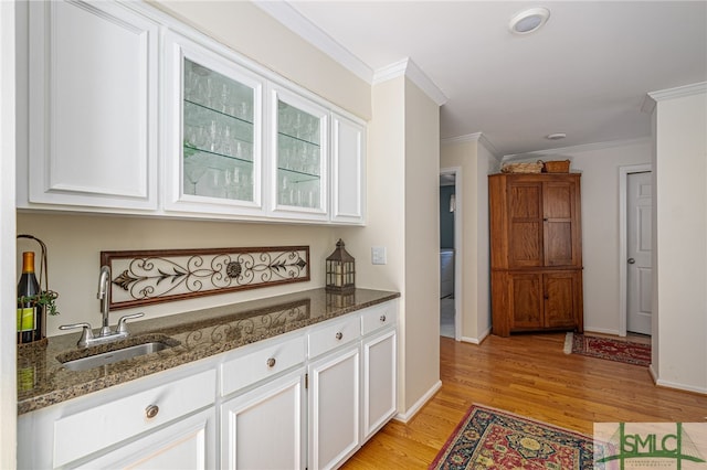 bar featuring sink, dark stone countertops, and white cabinets