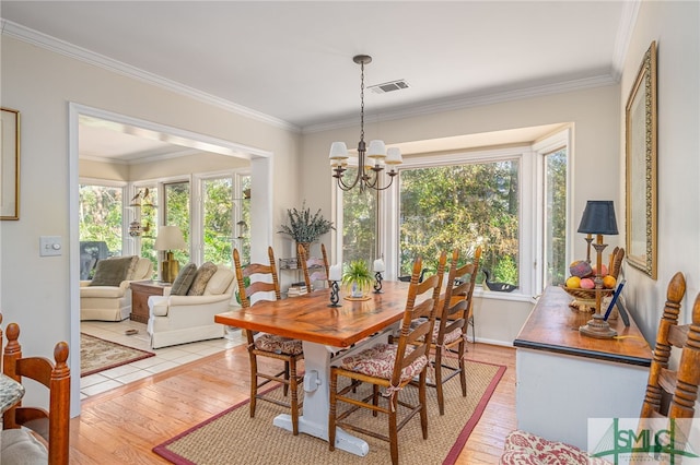 dining area featuring ornamental molding, light hardwood / wood-style floors, and a chandelier