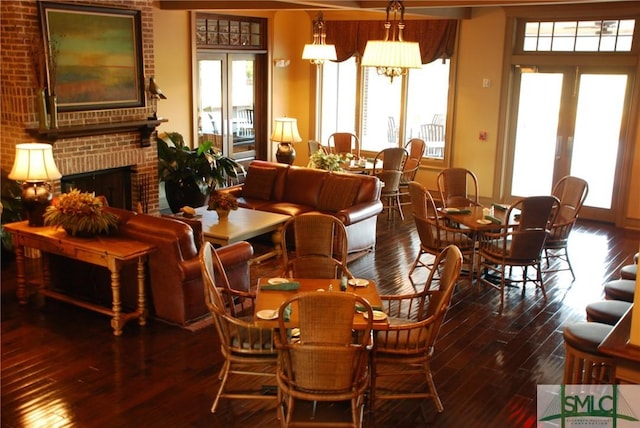 dining space with dark wood-type flooring, a notable chandelier, a fireplace, and french doors