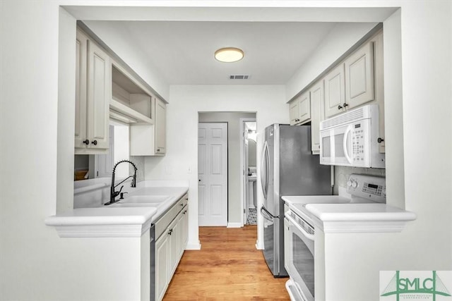 kitchen with stainless steel refrigerator, tasteful backsplash, sink, stove, and light hardwood / wood-style floors