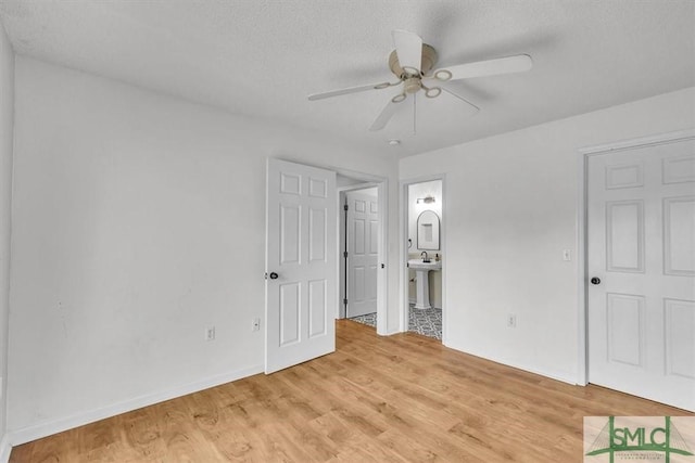 unfurnished bedroom with sink, ensuite bath, a textured ceiling, light wood-type flooring, and ceiling fan