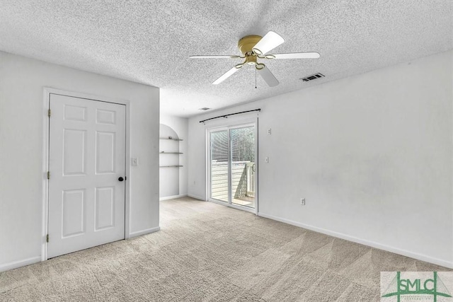 carpeted spare room featuring ceiling fan and a textured ceiling