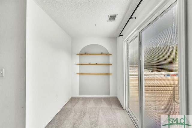 hall with light colored carpet and a textured ceiling