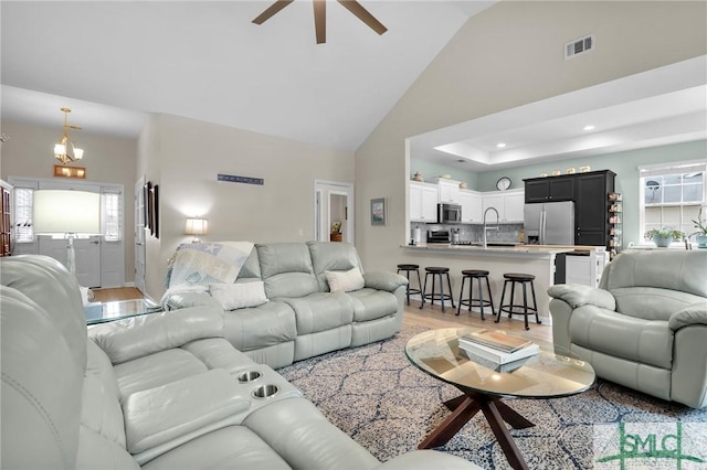 living room featuring high vaulted ceiling, sink, a wealth of natural light, and light wood-type flooring