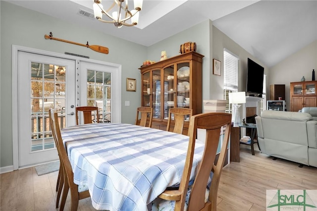 dining space with an inviting chandelier, vaulted ceiling, and light hardwood / wood-style floors