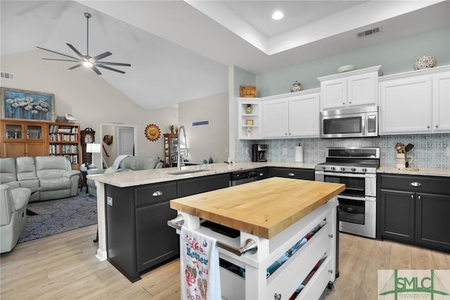 kitchen with kitchen peninsula, a center island, white cabinets, and appliances with stainless steel finishes