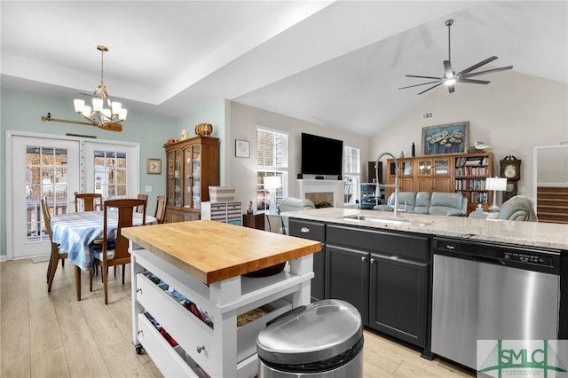 kitchen featuring dishwasher, hanging light fixtures, light stone counters, vaulted ceiling, and light wood-type flooring