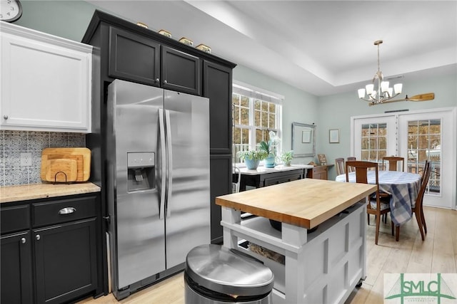 kitchen featuring stainless steel fridge with ice dispenser, tasteful backsplash, white cabinetry, a tray ceiling, and light hardwood / wood-style flooring