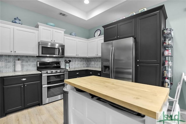 kitchen with stainless steel appliances, light hardwood / wood-style flooring, decorative backsplash, and white cabinets