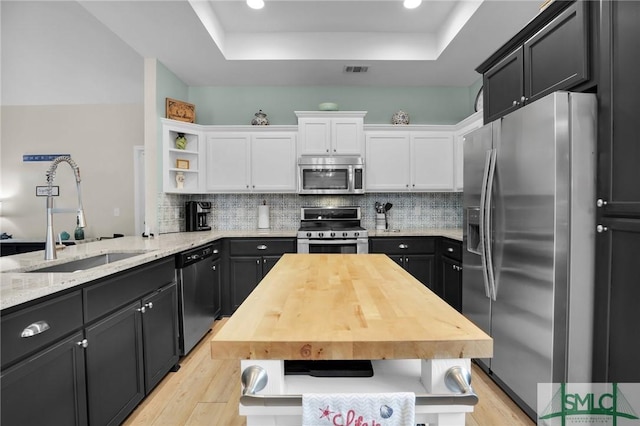 kitchen with white cabinetry, sink, decorative backsplash, kitchen peninsula, and stainless steel appliances