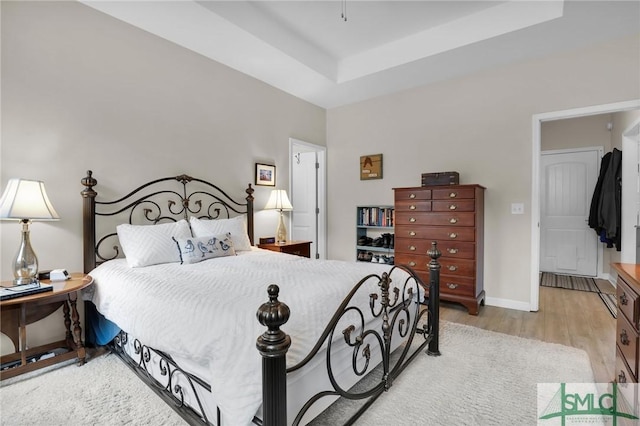 bedroom featuring a tray ceiling and light hardwood / wood-style floors