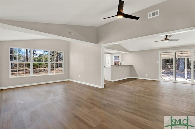 unfurnished living room with hardwood / wood-style flooring, vaulted ceiling, and ceiling fan