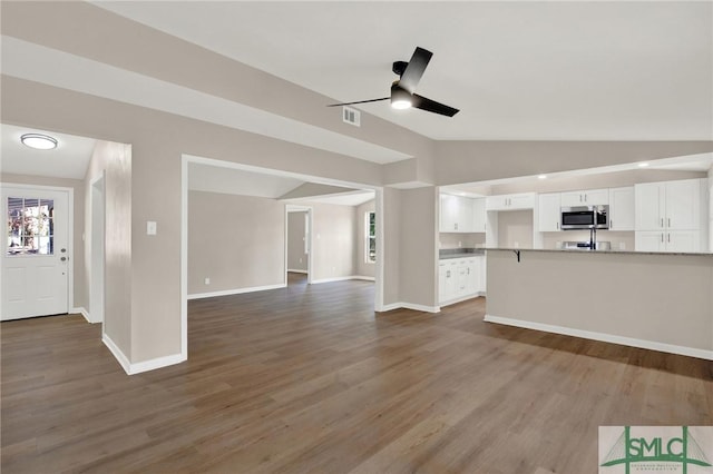 unfurnished living room featuring lofted ceiling, dark hardwood / wood-style floors, and ceiling fan