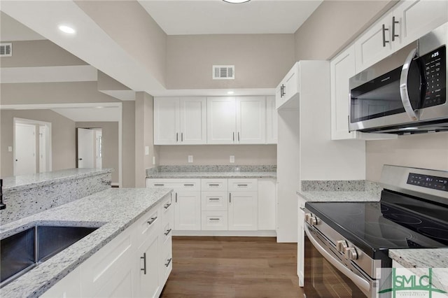 kitchen with sink, light stone counters, wood-type flooring, appliances with stainless steel finishes, and white cabinets