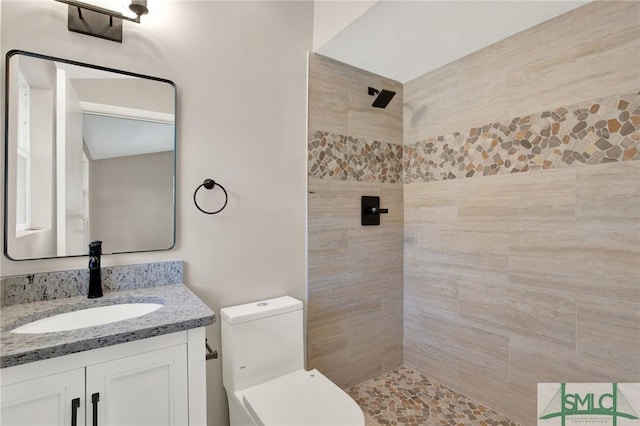 bathroom with vanity, tiled shower, and toilet