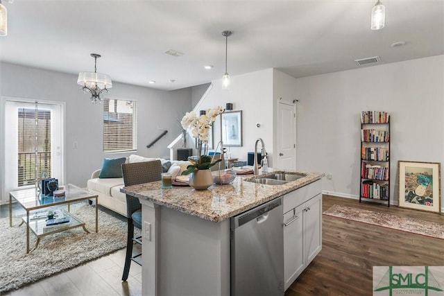 kitchen featuring an island with sink, sink, white cabinets, hanging light fixtures, and stainless steel dishwasher