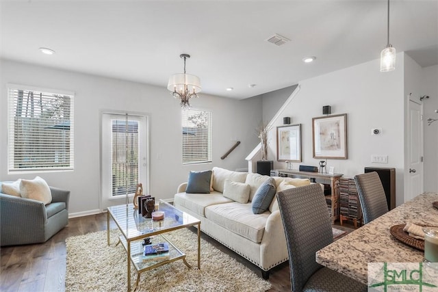 living room featuring dark wood-type flooring, plenty of natural light, and a chandelier