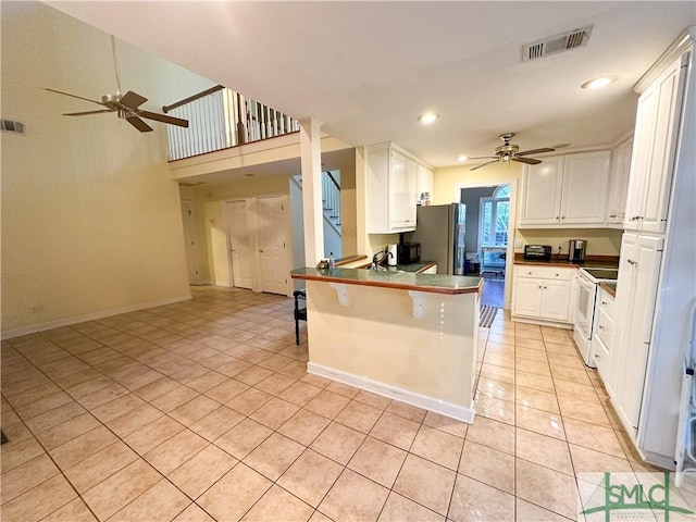 kitchen with a breakfast bar area, a peninsula, visible vents, white cabinets, and white range with electric stovetop