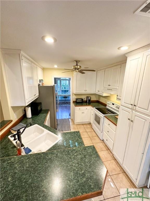 kitchen featuring dark countertops, a sink, white cabinets, and electric stove