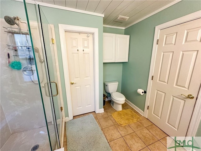 bathroom featuring toilet, ornamental molding, a stall shower, tile patterned flooring, and baseboards