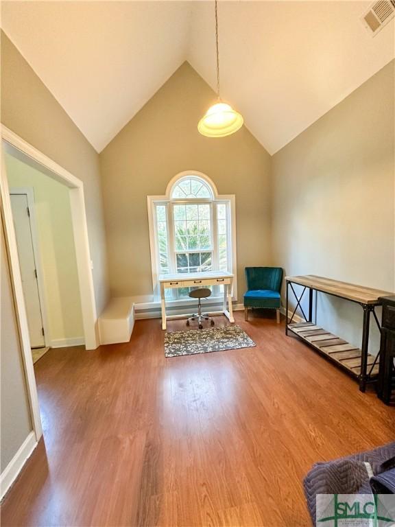 unfurnished room featuring lofted ceiling, baseboards, visible vents, and wood finished floors