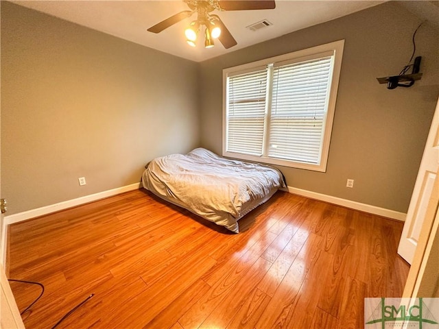 unfurnished bedroom featuring visible vents, ceiling fan, baseboards, and wood finished floors