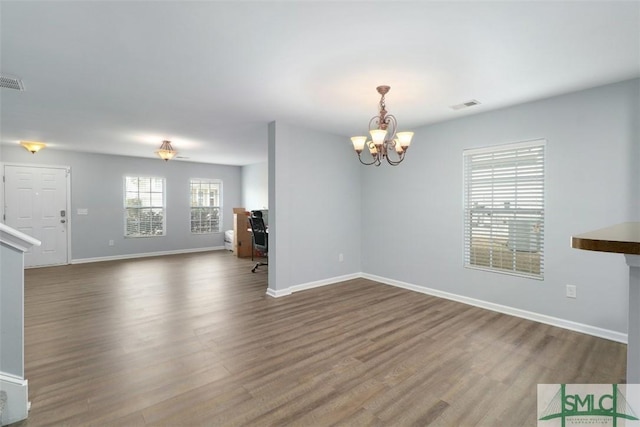 empty room featuring a chandelier and hardwood / wood-style floors