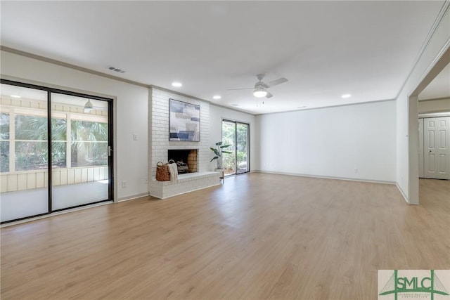 unfurnished living room featuring ceiling fan, ornamental molding, a fireplace, and light hardwood / wood-style floors