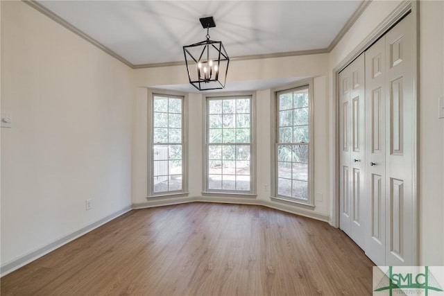 unfurnished dining area with an inviting chandelier, crown molding, and light hardwood / wood-style floors