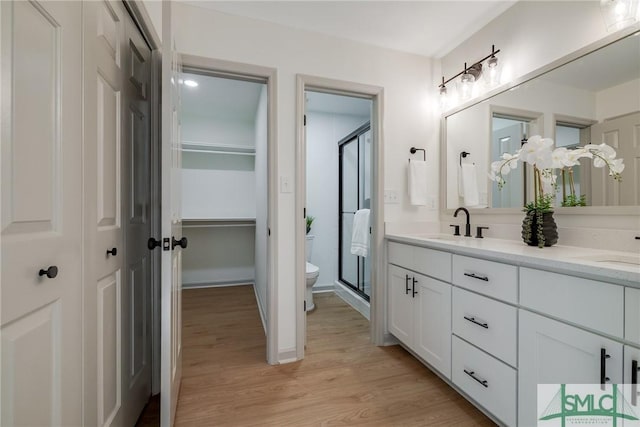 bathroom featuring vanity, toilet, hardwood / wood-style floors, and a shower with shower door