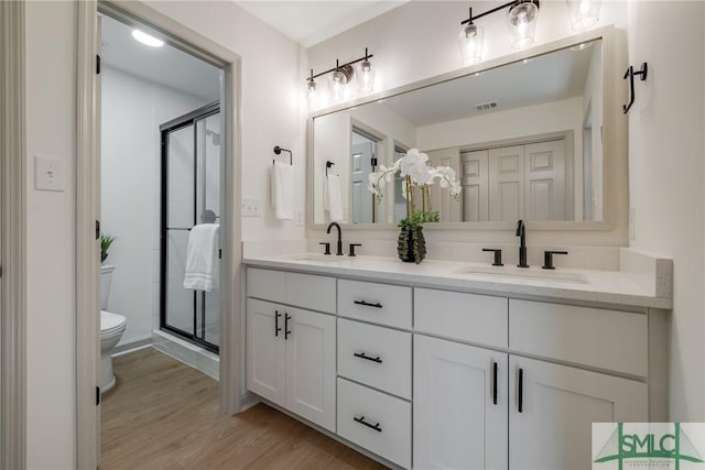 bathroom featuring walk in shower, hardwood / wood-style floors, vanity, and toilet