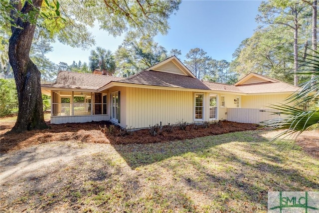 view of home's exterior featuring a sunroom and a lawn