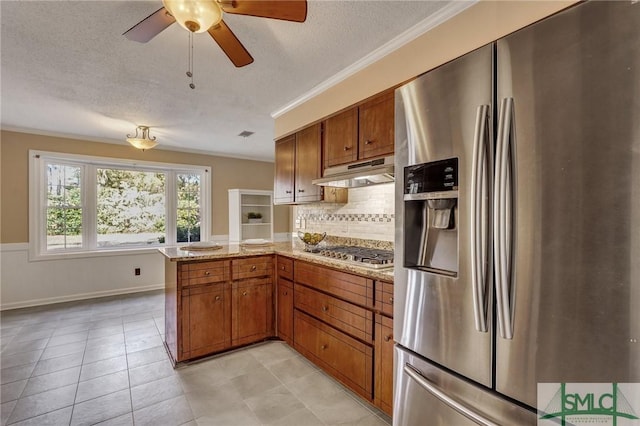 kitchen with appliances with stainless steel finishes, decorative backsplash, ornamental molding, kitchen peninsula, and a textured ceiling