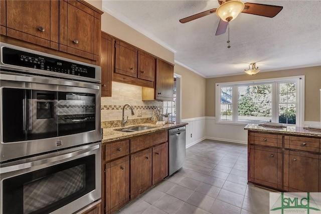 kitchen with sink, decorative backsplash, light tile patterned floors, stainless steel appliances, and light stone countertops